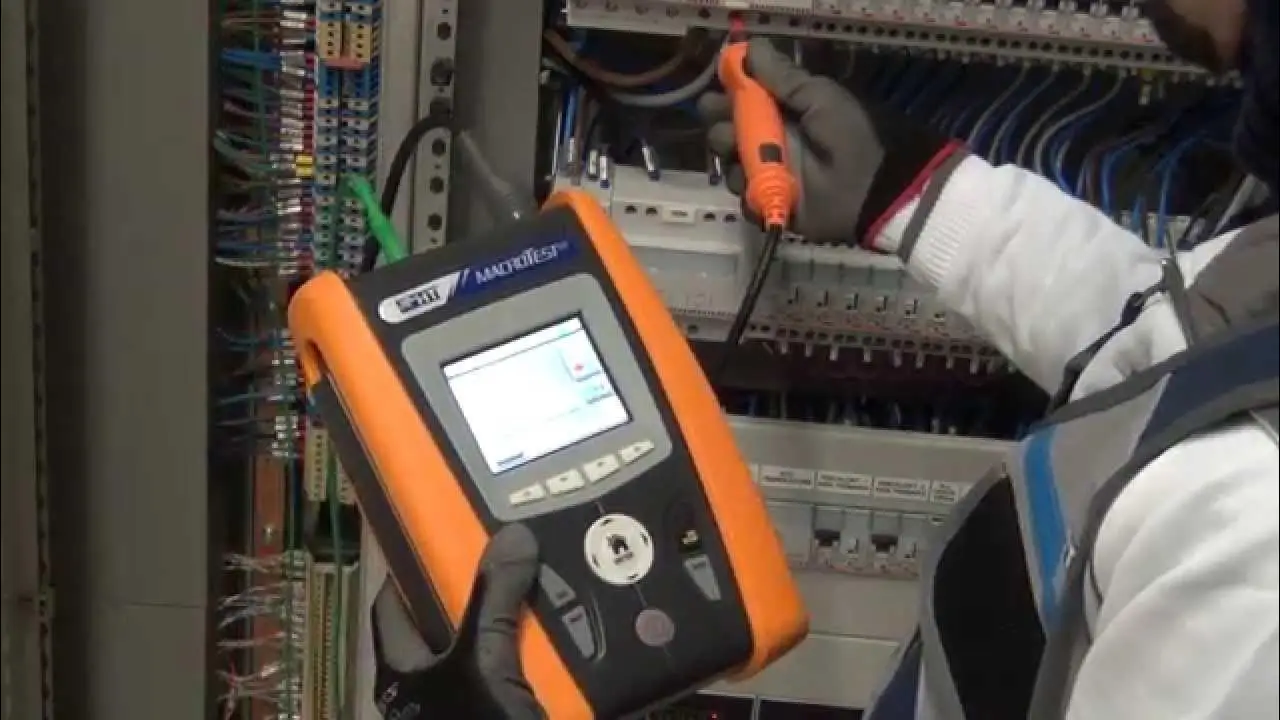Technician using an advanced electrical testing device to inspect and troubleshoot an industrial electrical panel.